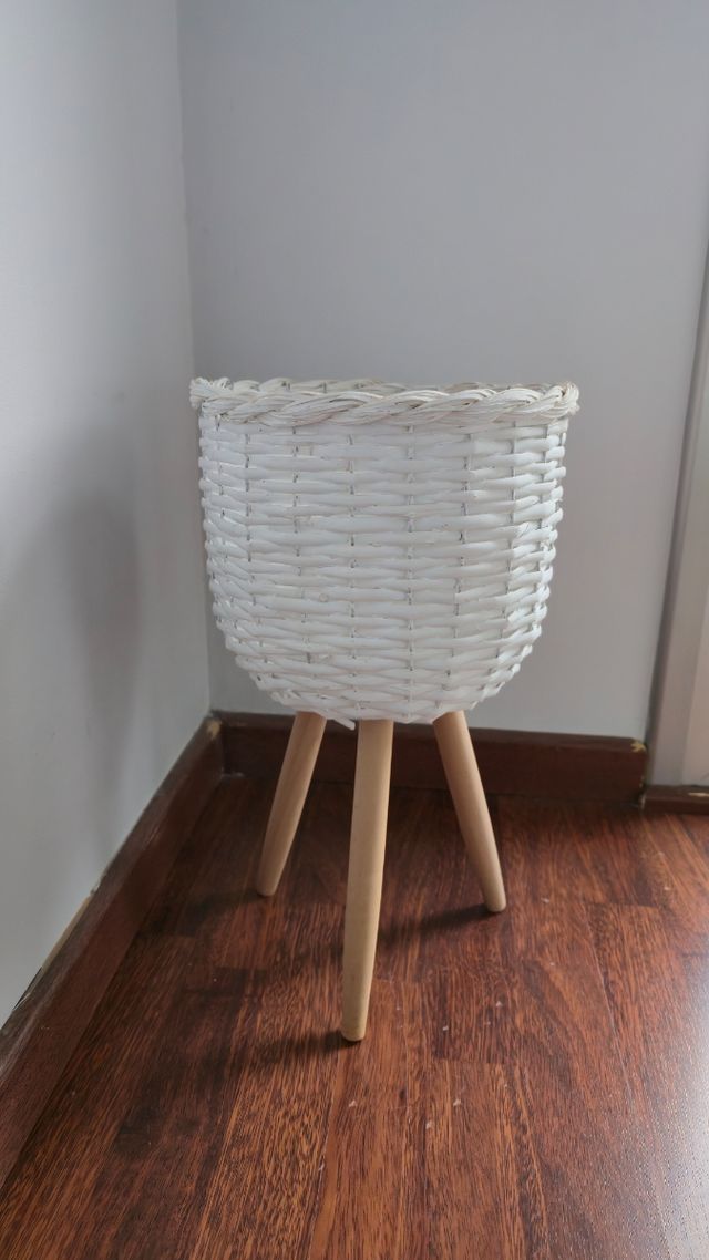 Macetero blanco de mimbre y planta artificial.