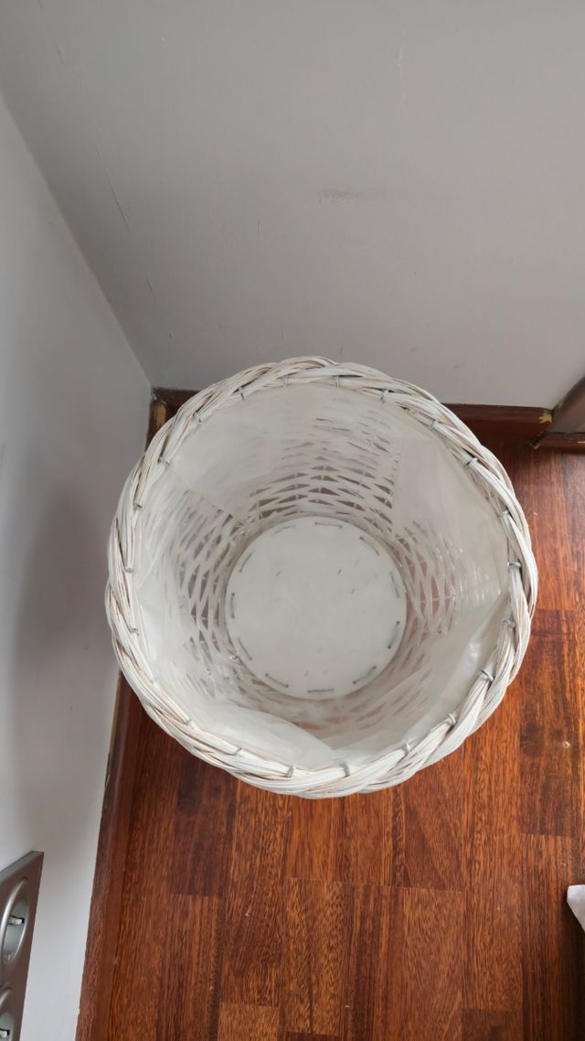 Macetero blanco de mimbre y planta artificial.