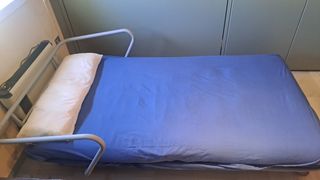 Sofá cama de futón azul con somier de lamas.