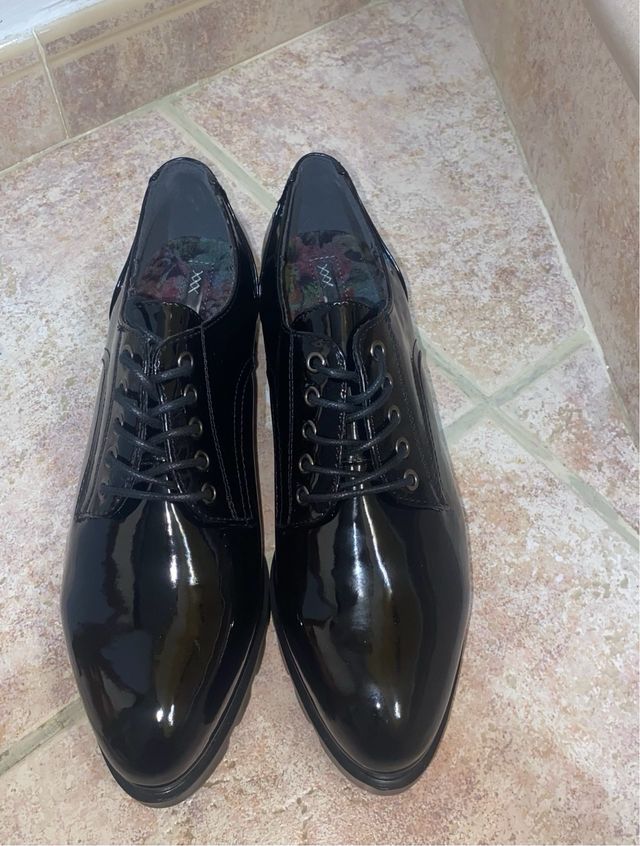 Zapatos negros charol con cordones.