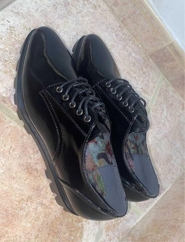 Zapatos negros charol con cordones.