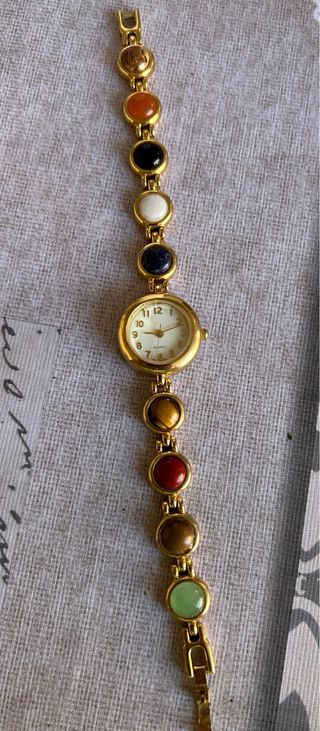 Reloj dorado con piedras multicolor