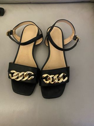 Sandalias planas negras con cadena dorada