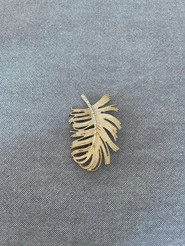 Broche dorada con forma de pluma – Elegancia clási