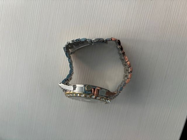 Reloj dorado y plateado con brillantes.