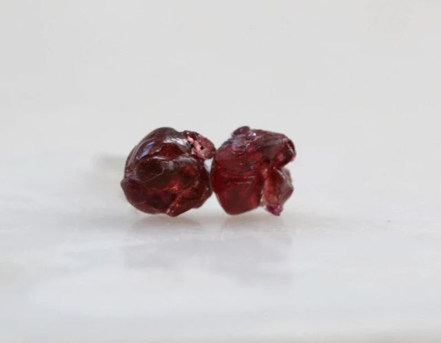 Un pendiente de granate rojo en crudo. Arete