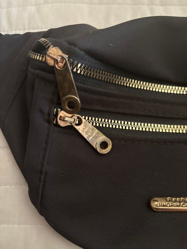 Riñonera negra con detalles dorados dos bolsillos.