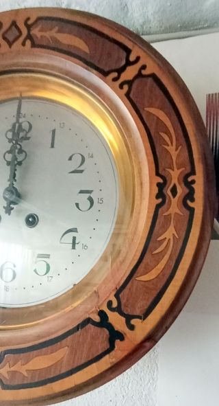 Antiguo reloj de pared de madera tipo ojo de buey.