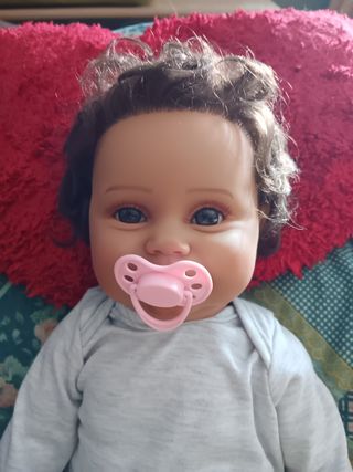 Muñeco reborn bebé, morenito, con pelo rizado.