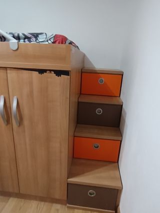 Cama alta con armario y cajonero debajo.