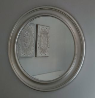 Espejo redondo con marco plateado.