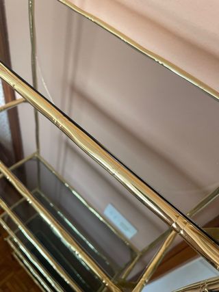 Estantería dorada con estantes de cristal