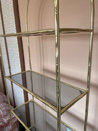 Estantería dorada con estantes de cristal