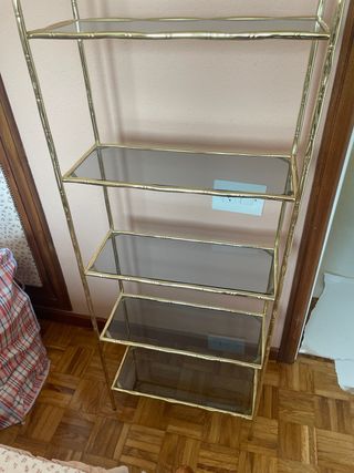Estantería dorada con estantes de cristal