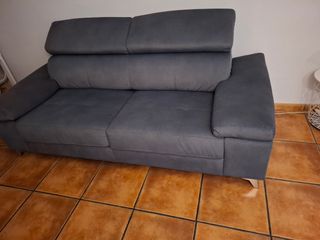 Sofá gris con almacenamiento en brazo.