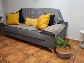 Sofá gris con almacenamiento en brazo.
