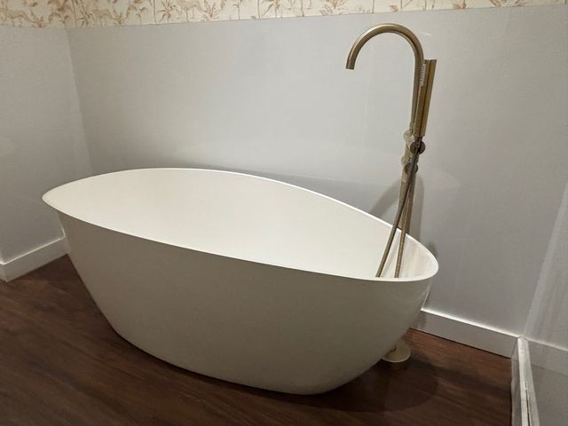 Bañera isla, acrílica blanca y grifería dorada.