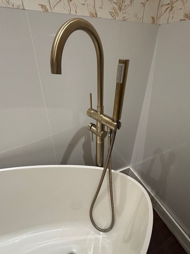 Bañera isla, acrílica blanca y grifería dorada.