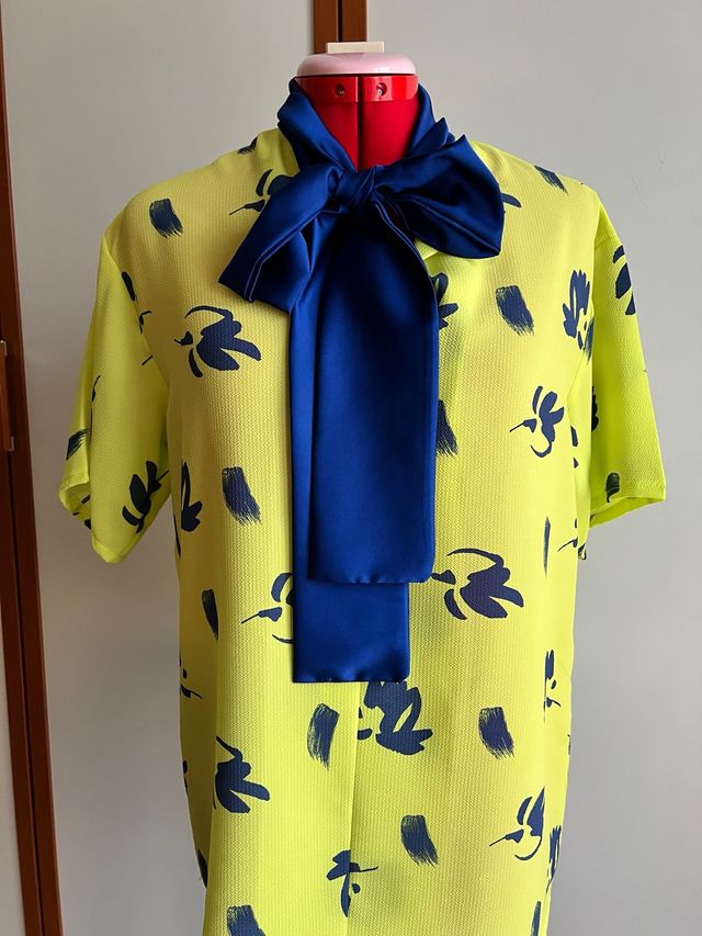 Blusa gialla con fiocco blu
