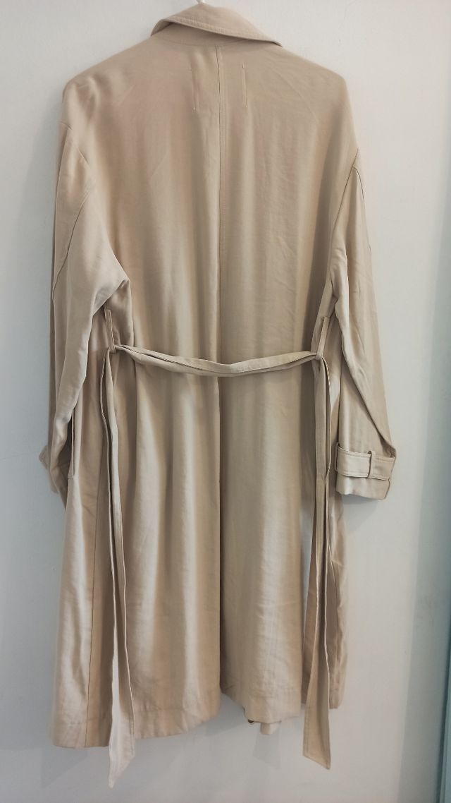 Gabardina beige larga con cinturón y bolsillos.