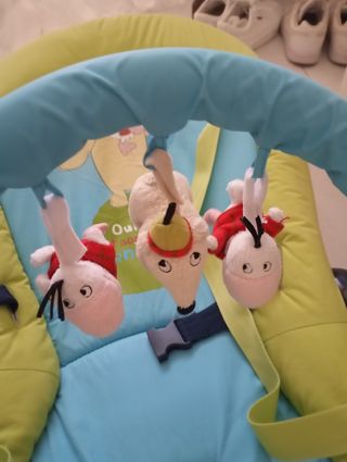 Lettino per bambini, con bambole appese per giocare.