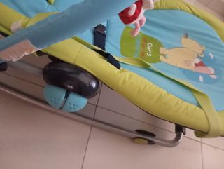 Lettino per bambini, con bambole appese per giocare.