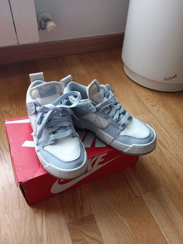 Zapatillas Nike altas azul-blanco y logo en beige.