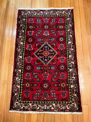 Alfombra oriental roja con diseño tradicional.