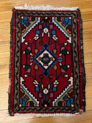Alfombra oriental roja con diseño tradicional.