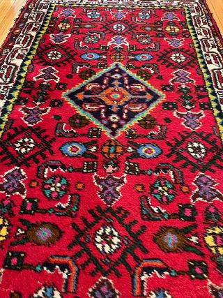 Alfombra oriental roja con diseño tradicional.