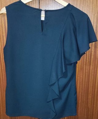 Blusa negra elegante con volantes en un lateral.
