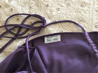 Mono de raso morado. Atado al cuello con tirantes.