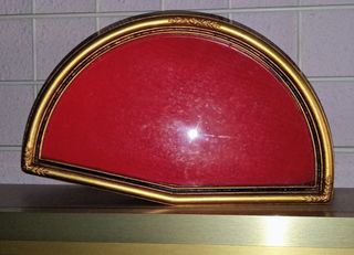 Marco abanico dorado con fondo aterciopelado rojo