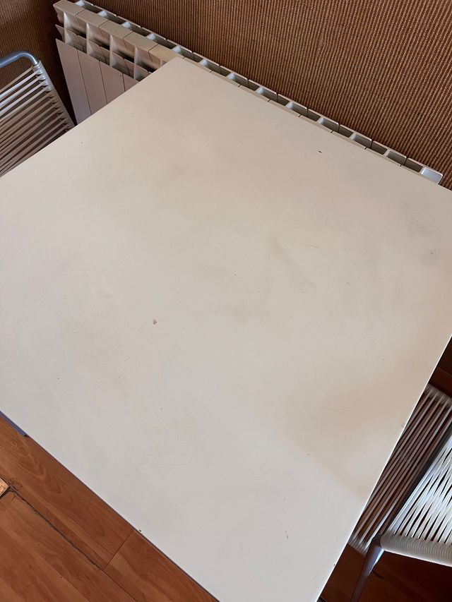 Tavolo in metallo grigio e piano in legno bianco.