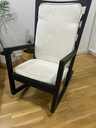 Mecedora de madera negra y cojines blancos