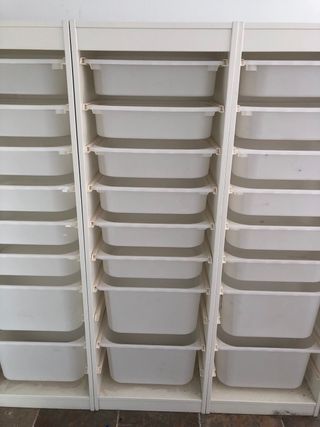 Cajonera blanca de madera con cajones de plástico.