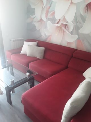 Sofá de tela rojo con mesa de cristal.
