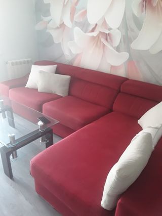 Sofá de tela rojo con mesa de cristal.
