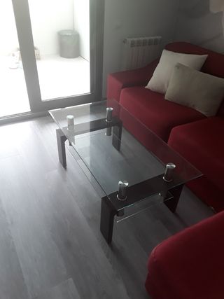 Sofá de tela rojo con mesa de cristal.
