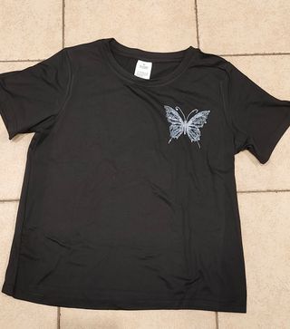 Camiseta negra con estampado de mariposa blanca.