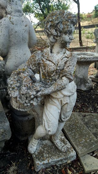 Estatua de piedra de niño con flores