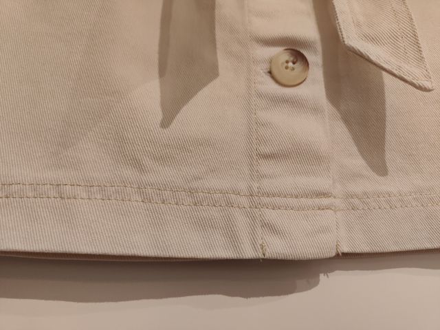 Falda vaquera corta beige con cinturón.