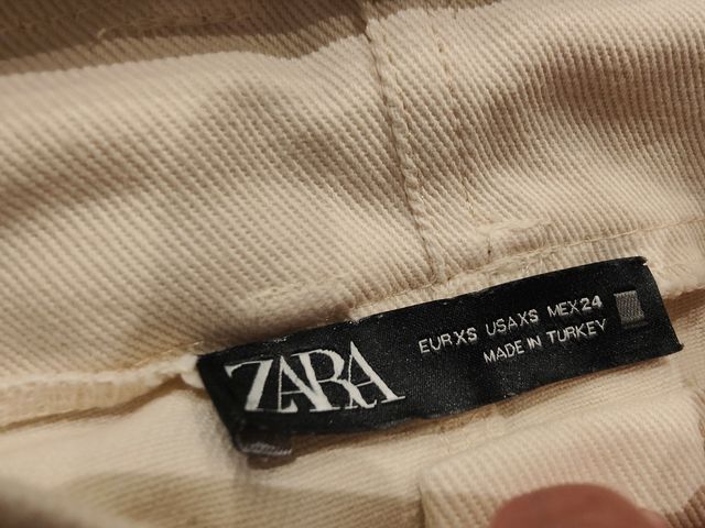 Falda vaquera corta beige con cinturón.