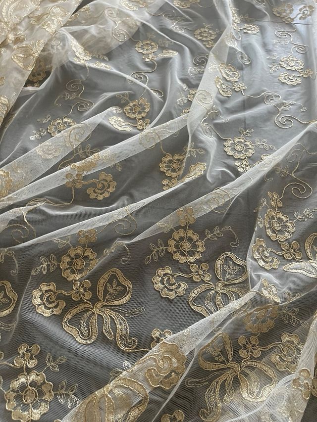 Tessuto in pizzo dorato su tulle