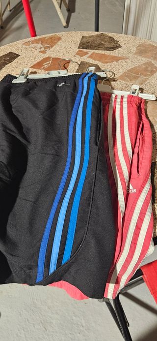 Dos pantalones deportivos Adidas negro y rojo.
