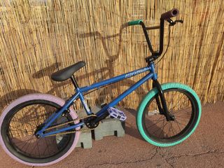 Bicicleta BMX azul con ruedas rosas y turquesa