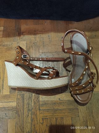 Sandalias marrones con cuña y tachuelas.