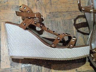 Sandalias marrones con cuña y tachuelas.
