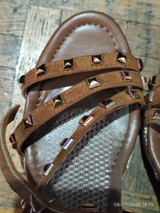 Sandalias marrones con cuña y tachuelas.