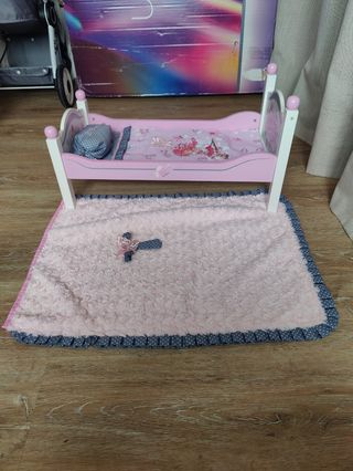 Cama de muñeca rosa con manta